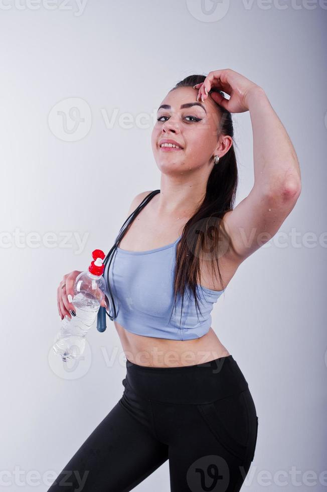 Wet cheerful attractive young fitness woman in top and black leggings with  jump rope and bottle of water isolated over white background. 10501476  Stock Photo at Vecteezy