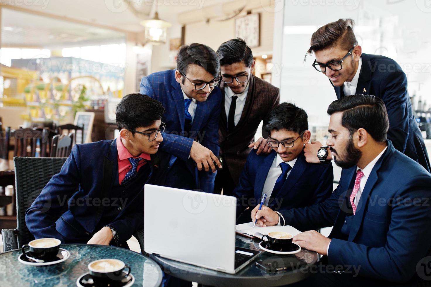 Collaborative process of indian business mans during brainstorming meeting in office.Diverse team of young people dressed in suits cooperating on developing common project. photo