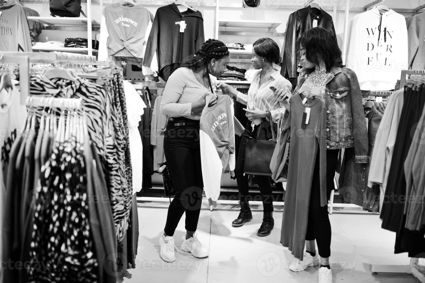 tres mujeres africanas eligiendo ropa en la tienda. dia de compras. foto