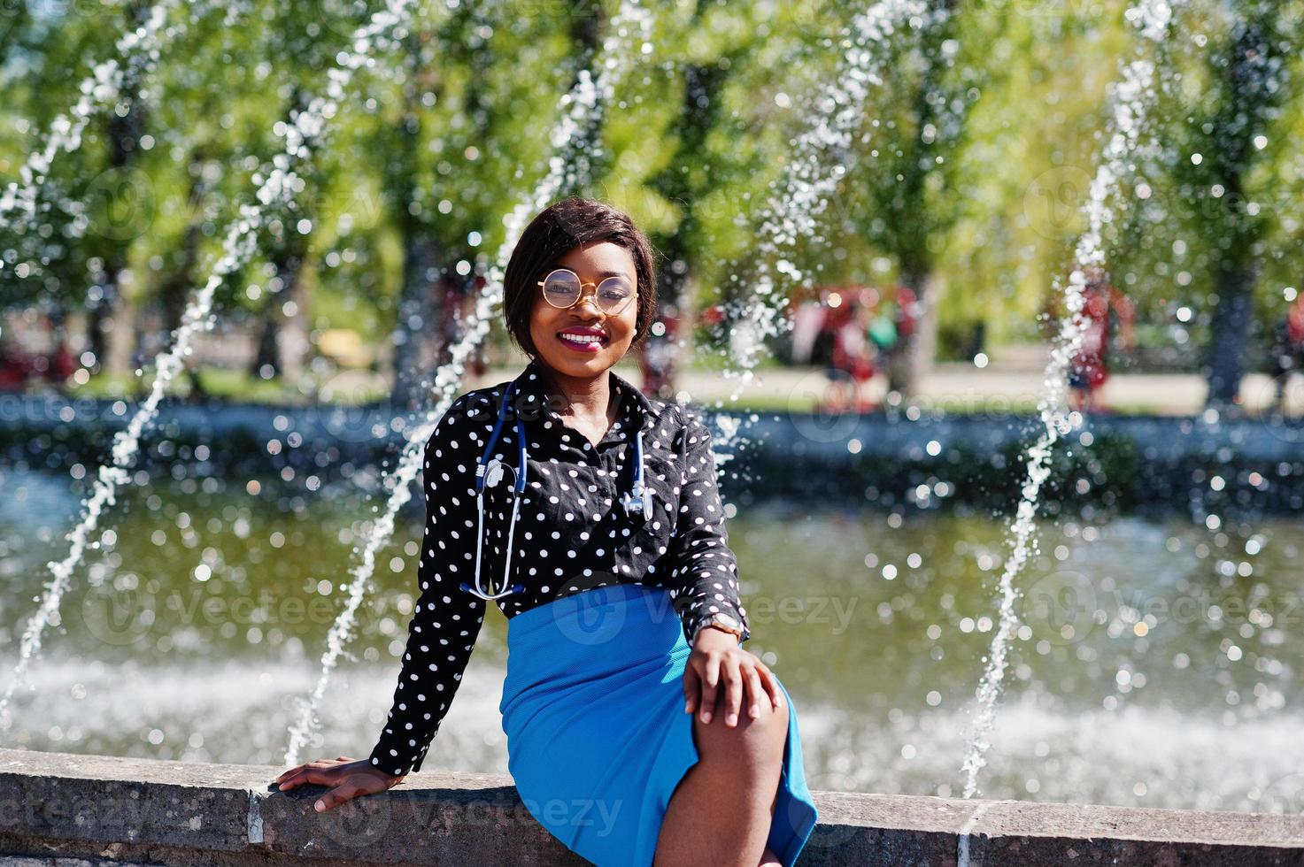 African american doctor female with stethoscope posed outdoor background fountains. photo