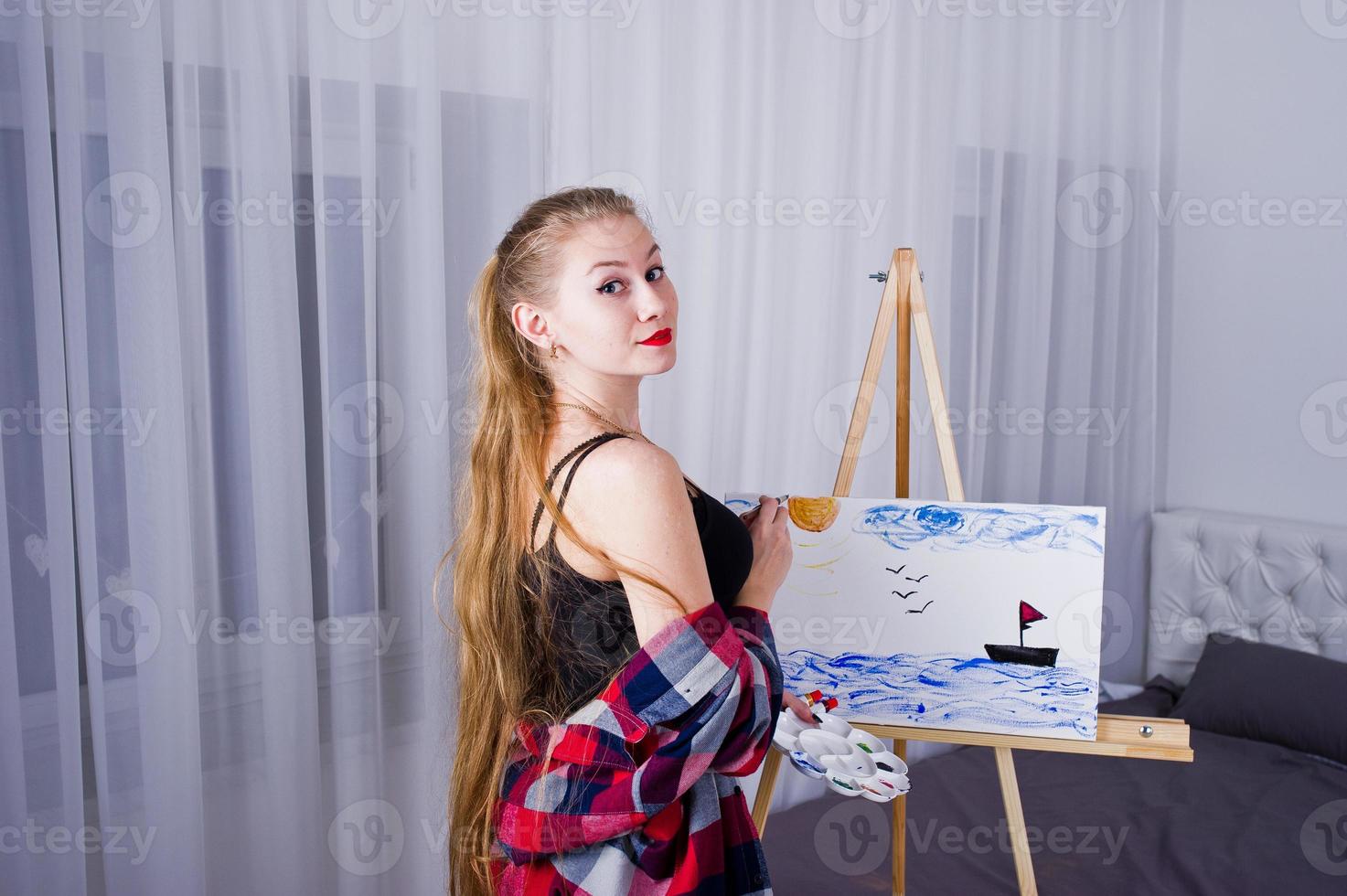 Beautiful woman artist painter with brushes and oil canvas posing bed at room. photo