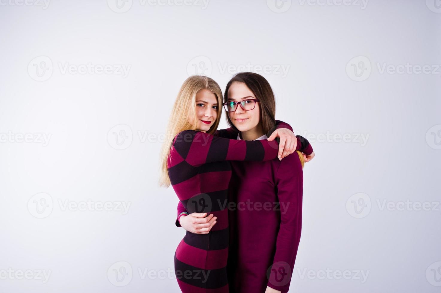 Portrait of two female friends in cherry dresses posing in the studio. photo