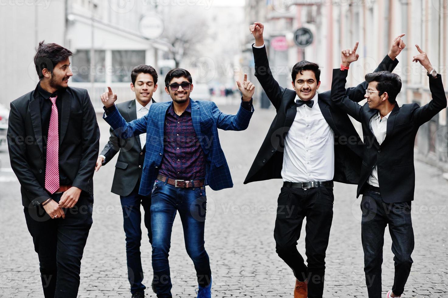 Group of 5 indian students in suits posed outdoor, having fun and dancing. photo