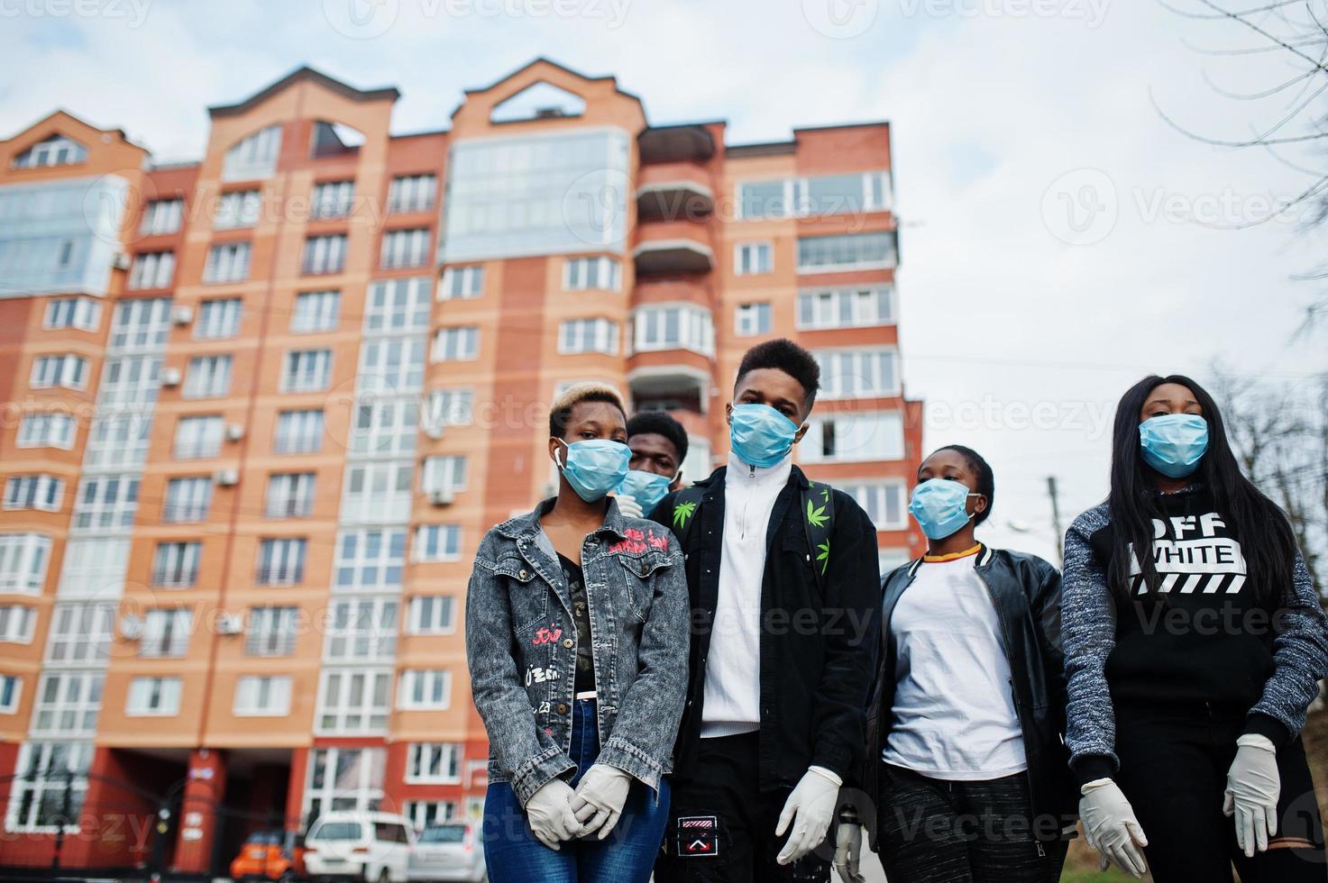 grupo de amigos adolescentes africanos contra la calle vacía con un edificio que usa máscaras médicas para protegerse de infecciones y enfermedades cuarentena del virus del coronavirus. foto