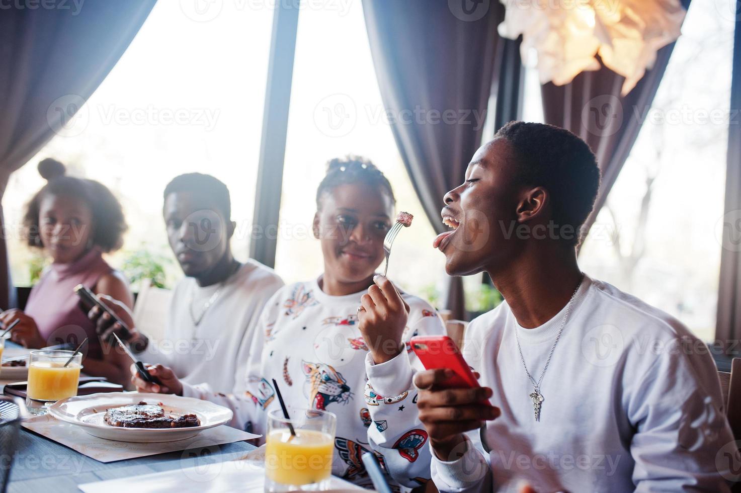 Happy african friends sitting, chatting in cafe and eat food. Group of black peoples meeting in restaurant and have dinner. photo