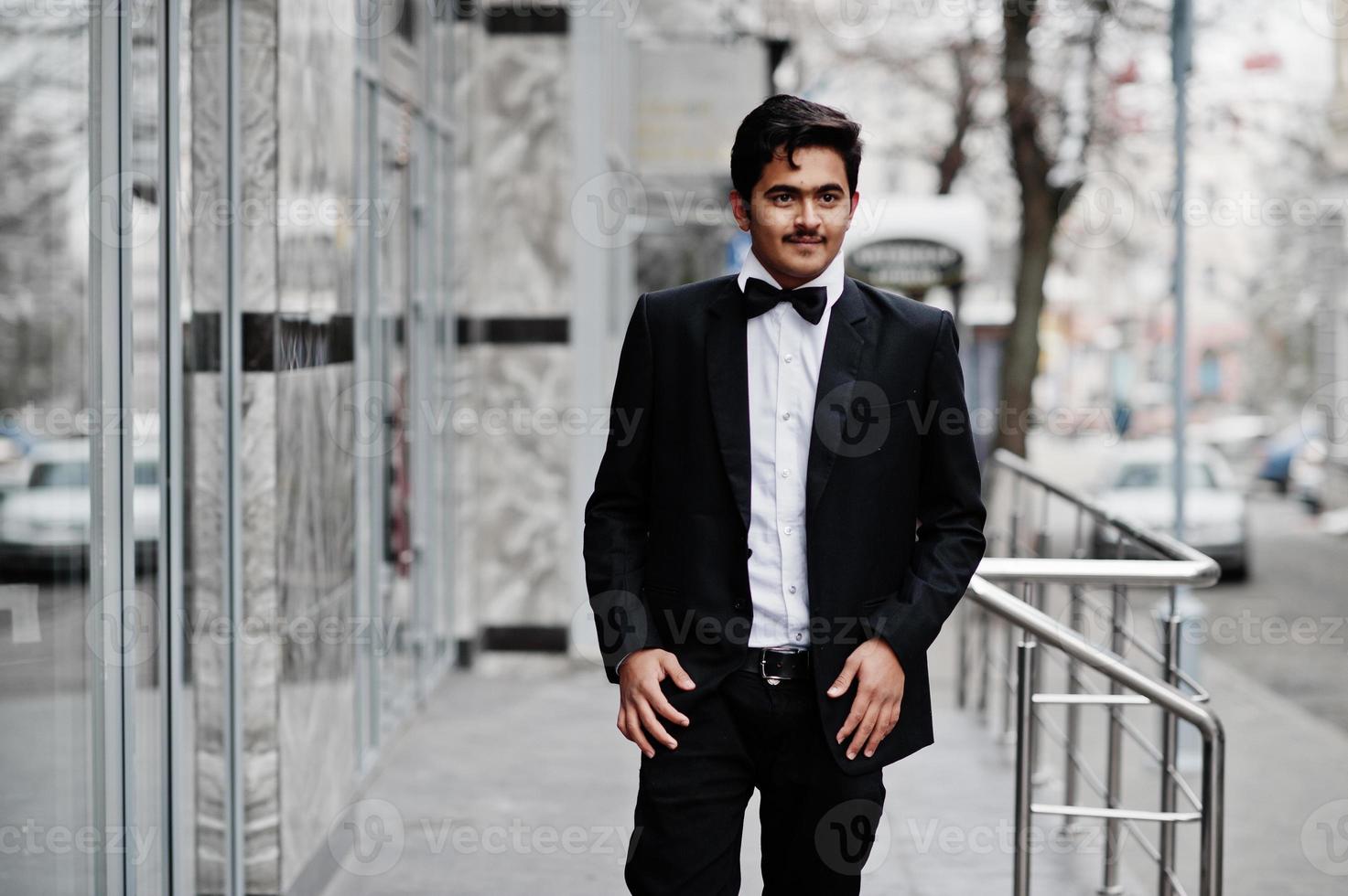 joven indio con traje negro y pajarita posó al aire libre. foto