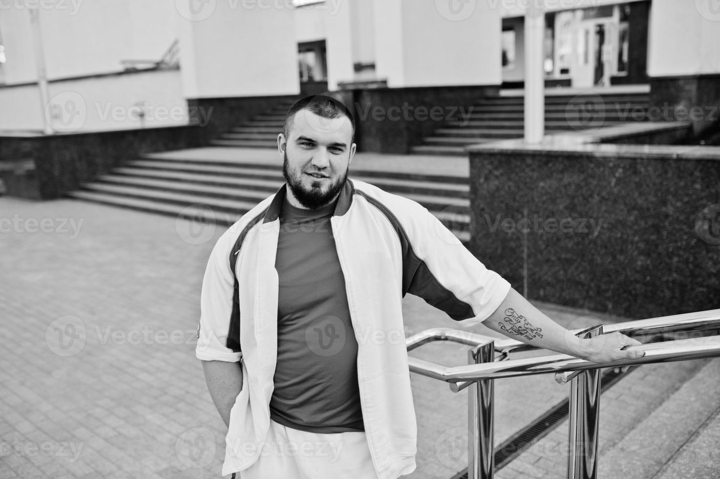 joven musculoso barbudo brutal vestido con traje deportivo blanco con camisa roja. foto