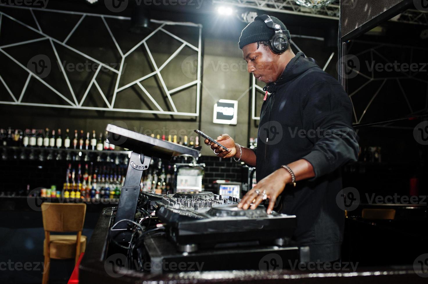 African american dj play music on decks at night club. photo