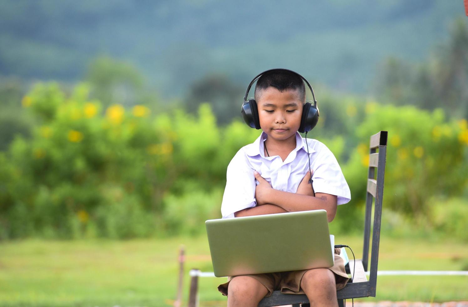 Schoolchildren enjoy listening to music with headphones on the lawn, redido headphones. photo