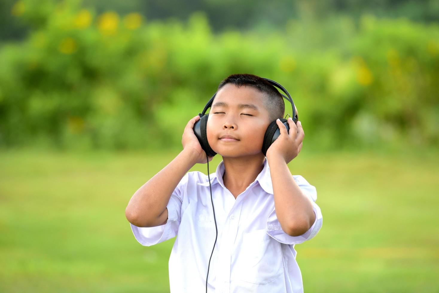 Schoolchildren enjoy listening to music with headphones on the lawn, redido headphones. photo