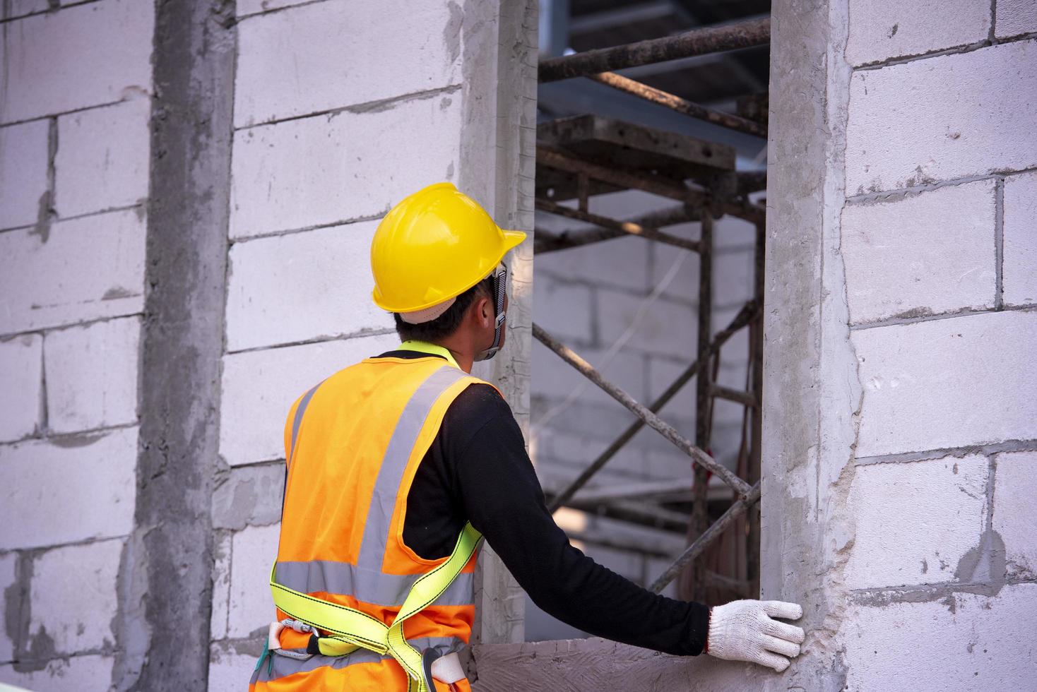 El albañil de ladrillo ligero está hecho de arcilla expandida. elementos en la construcción de mampostería el constructor sostiene los ladrillos un hombre que lleva un casco en un sitio de construcción foto