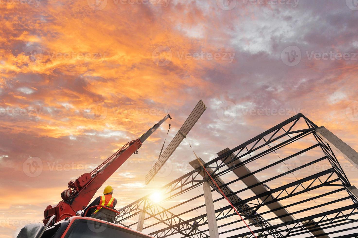 los trabajadores instalan nuevos techos usando grúas móviles. levante la lámina de techo de metal en el marco del techo. subir a la tienda por encima del techo de estructura de acero en el proyecto de construcción. foto