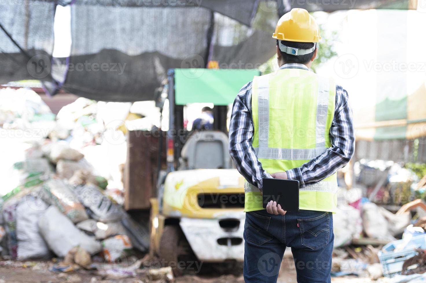 Close-up of a worker with a recycling bin moving a forklift in a steel mill waste collection plant. photo