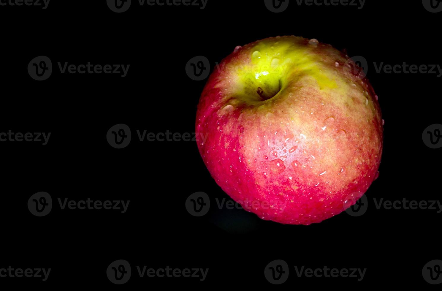 Water droplet on glossy surface of red apple on black background photo