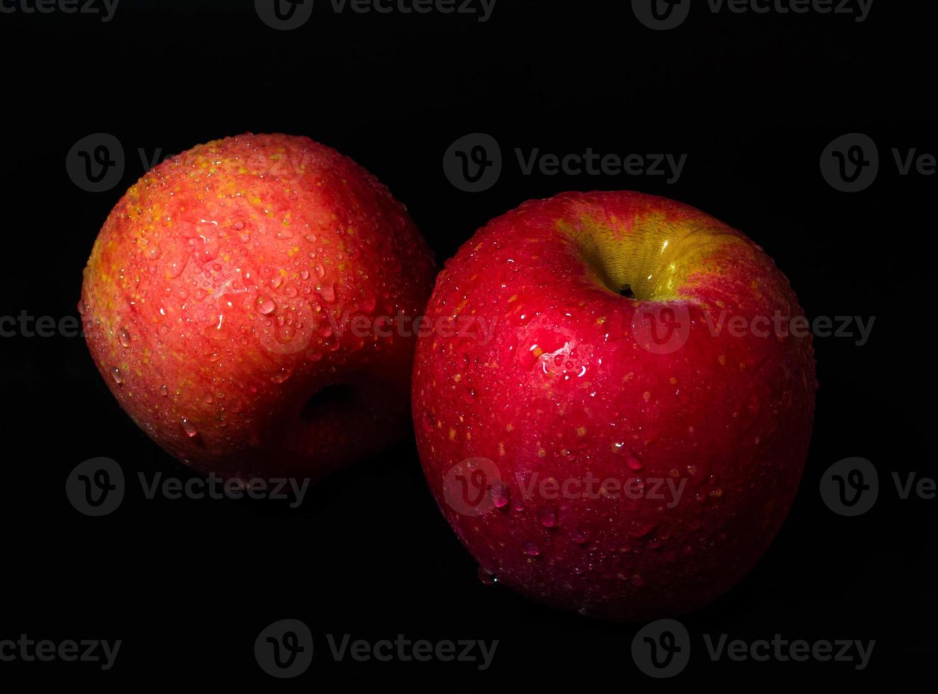 Gota de agua sobre la superficie brillante de la manzana roja sobre fondo negro foto