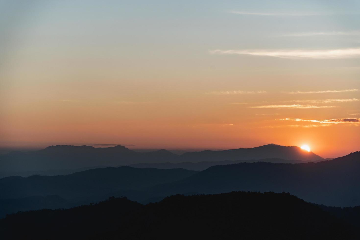 paisaje de puesta de sol con iluminación dorada de montaña y sol bajo un cielo nocturno vibrante y colorido en las montañas. naturaleza montaña cielo y nubes puesta de sol concepto foto