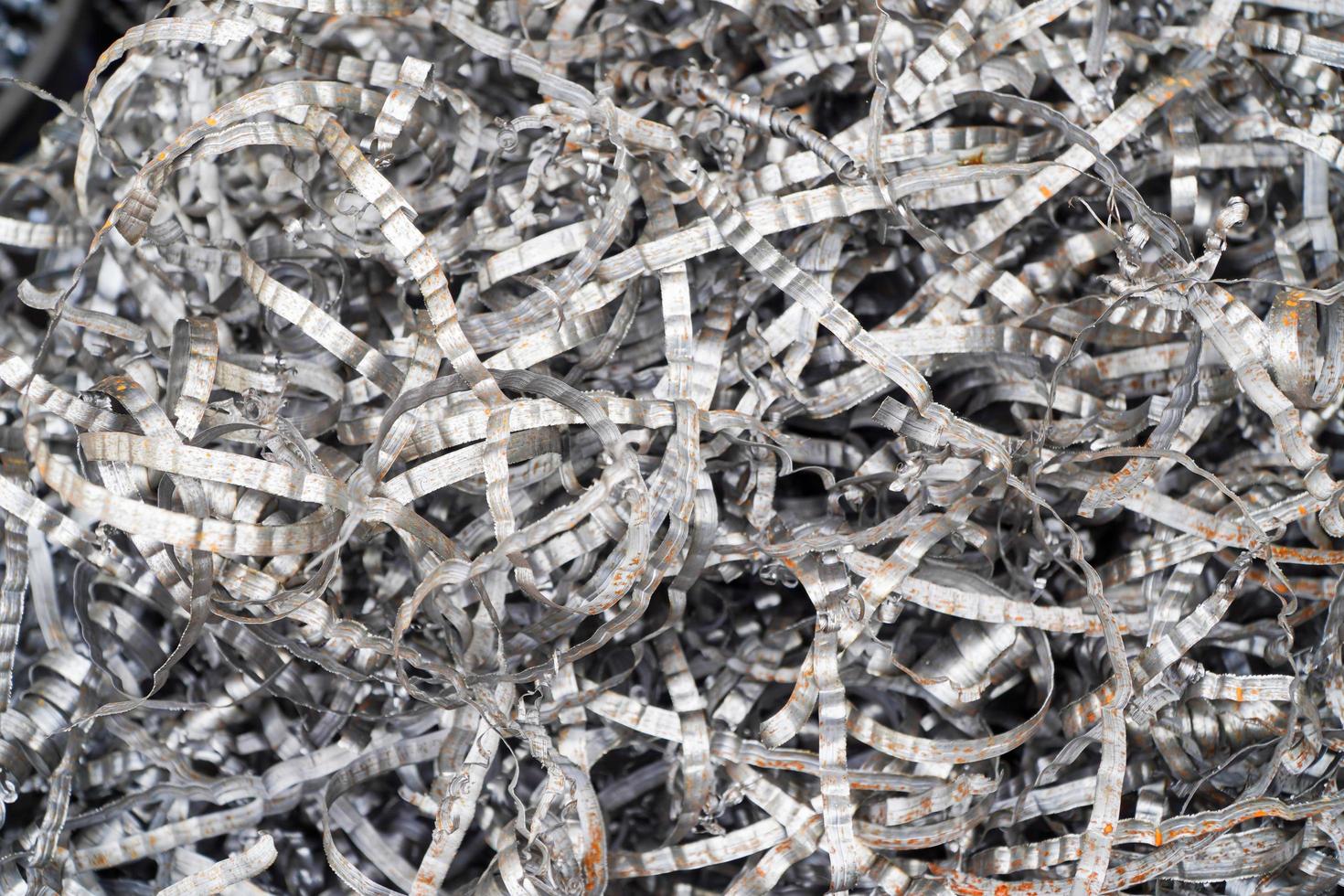 Steel scrap materials recycling. Aluminum chip waste after machining metal parts on a cnc lathe. Closeup twisted spiral steel shavings. Small roughness sharpness, photo