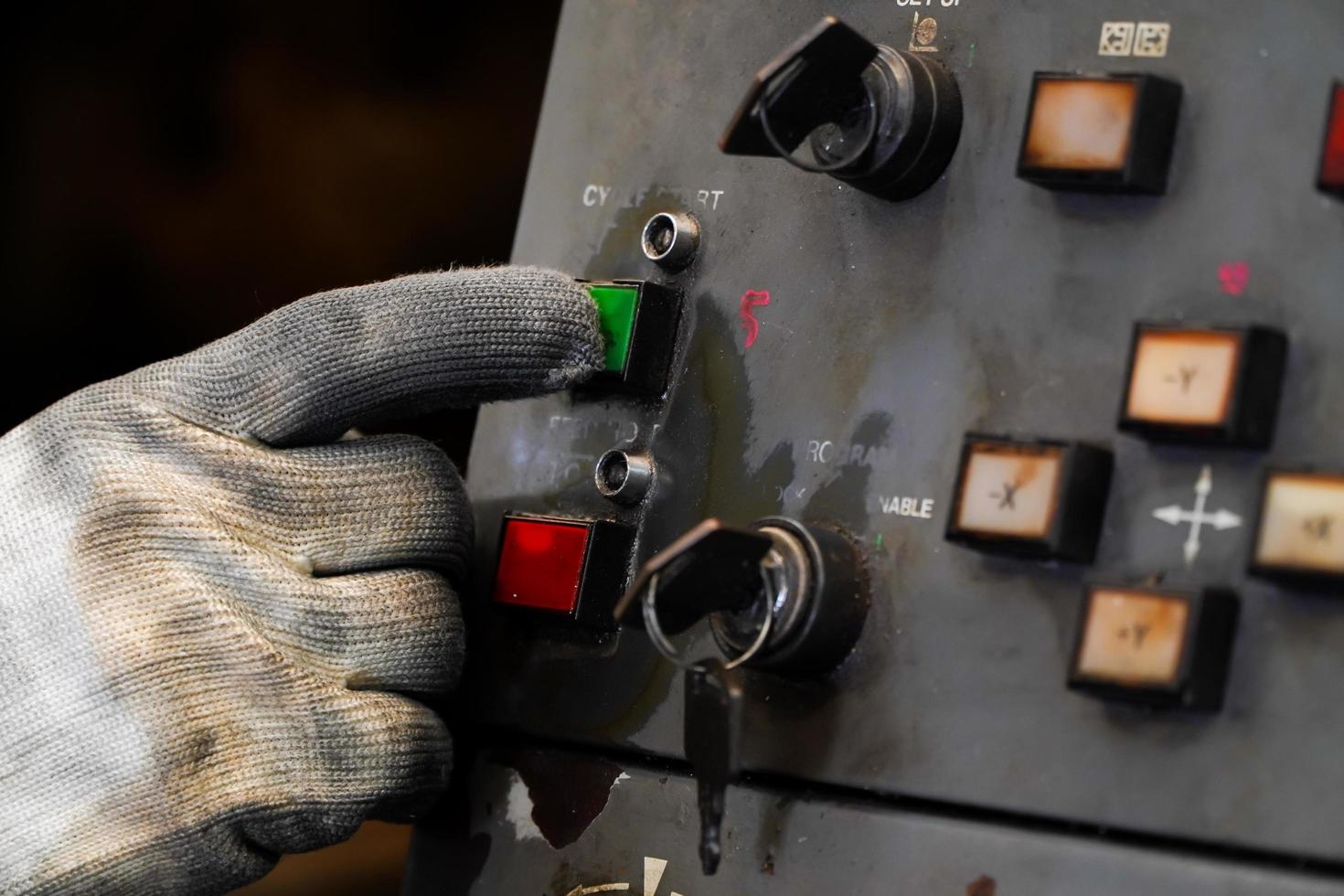 Dirty gloves press the green start button on the CNC machine control panel. photo