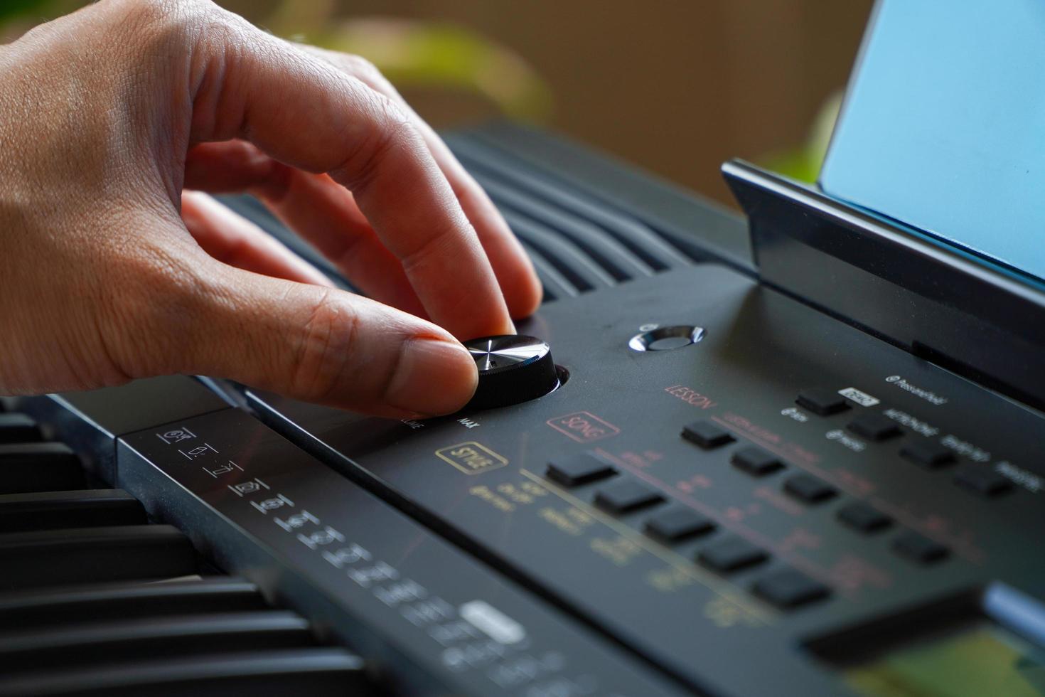 Man playing electronic music keyboard synthesizer with hands adding volume. photo