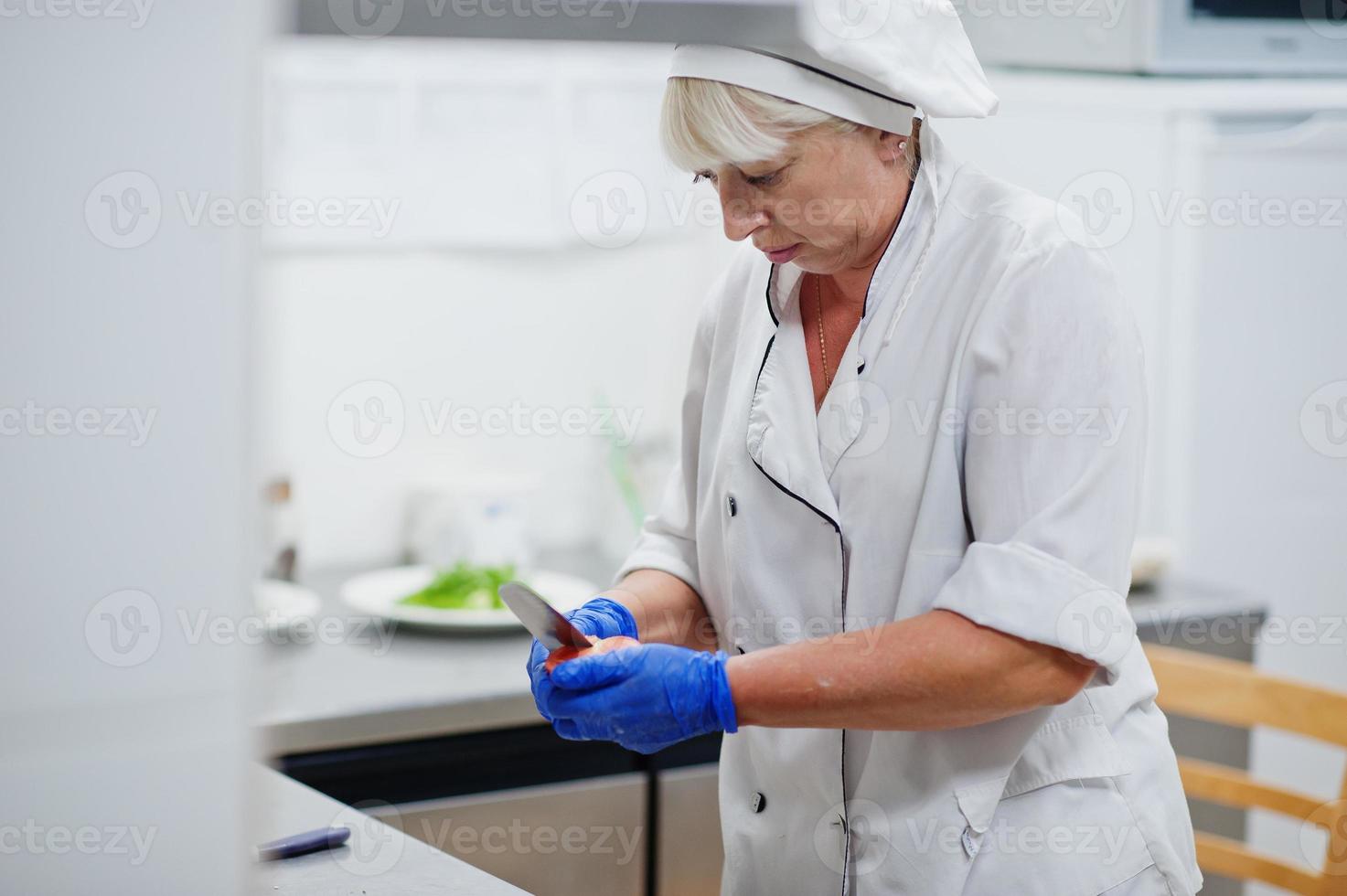 Female chef preparing salad in italian restaurant kitchen. photo