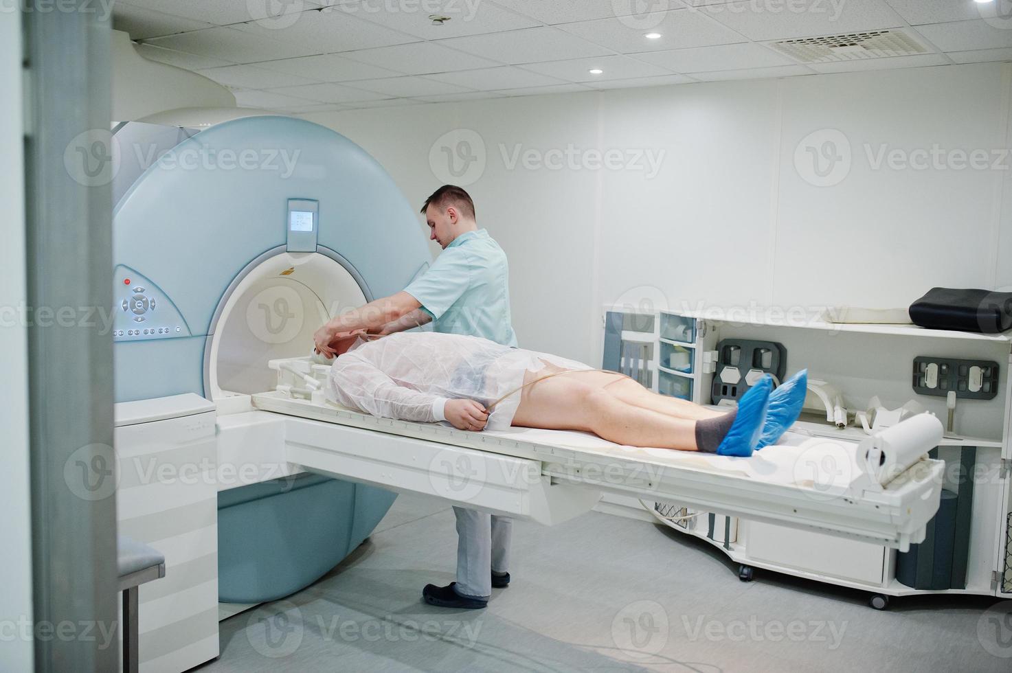 Male doctor turns on magnetic resonance imaging machine with patient inside. photo