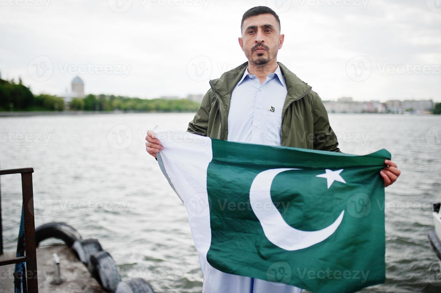 Traditional clothes indian pakistani male portrait hold Pakistan flag. photo