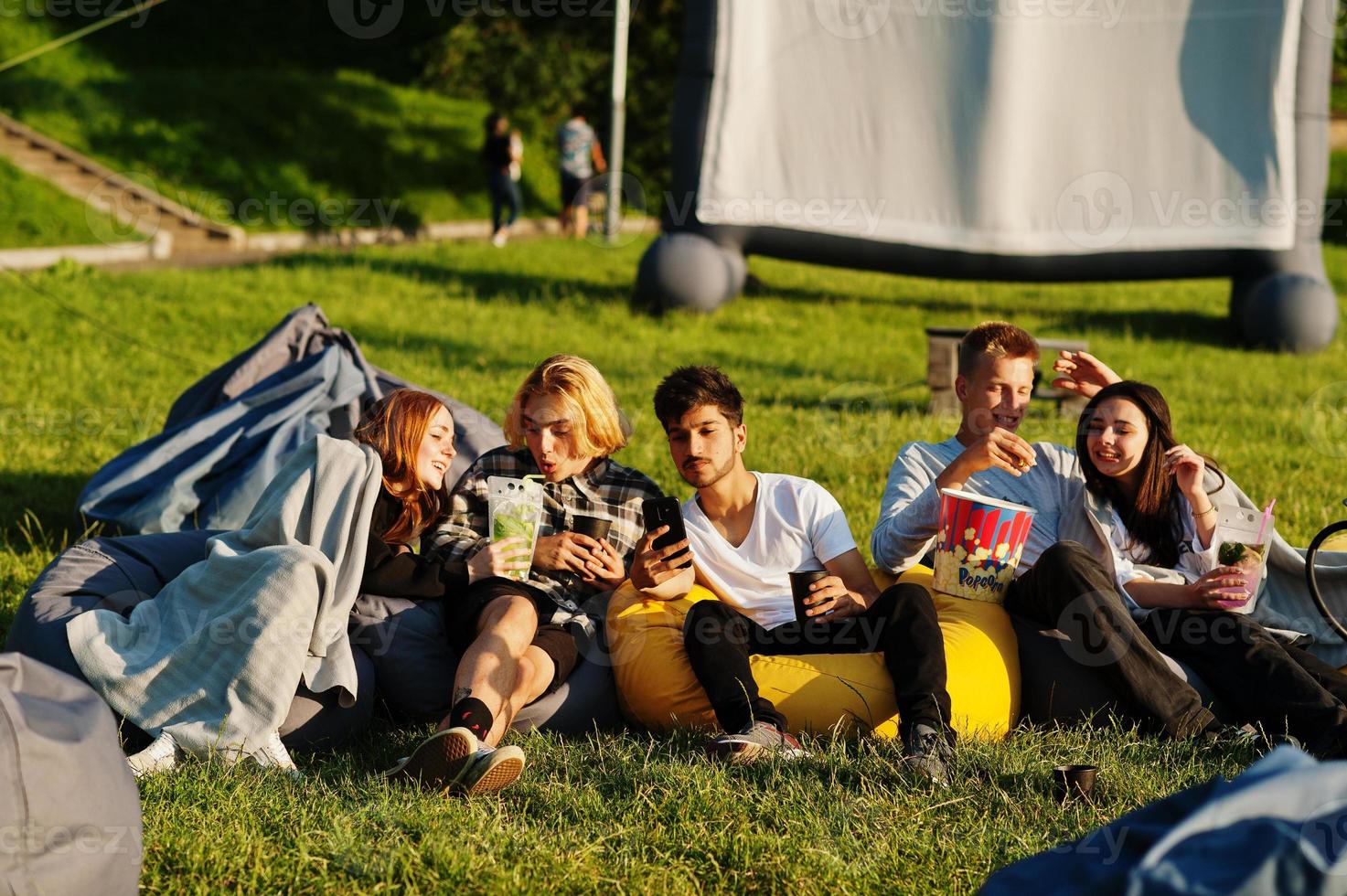 joven grupo multiétnico de personas viendo películas en poof en cine al aire libre. foto