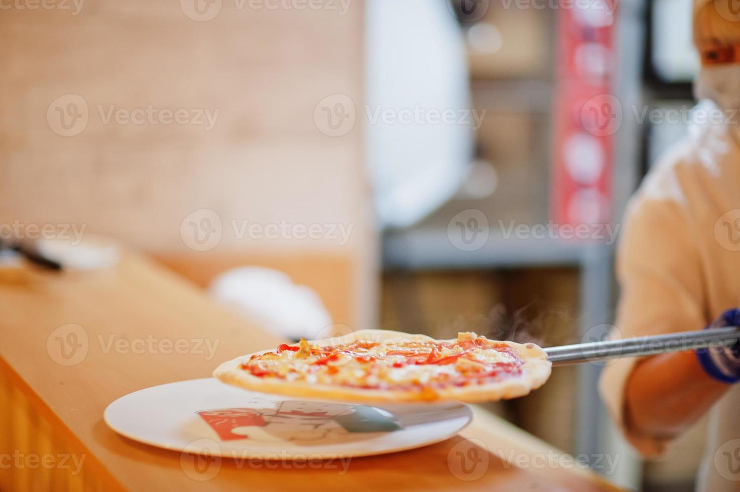 Feale chef preparing pizza in restaurant kitchen. photo