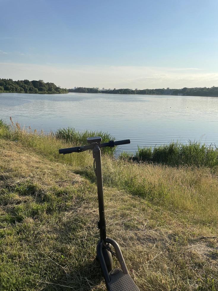 scooter eléctrico en un parque cerca del lago. el concepto de ecología y transporte eléctrico foto