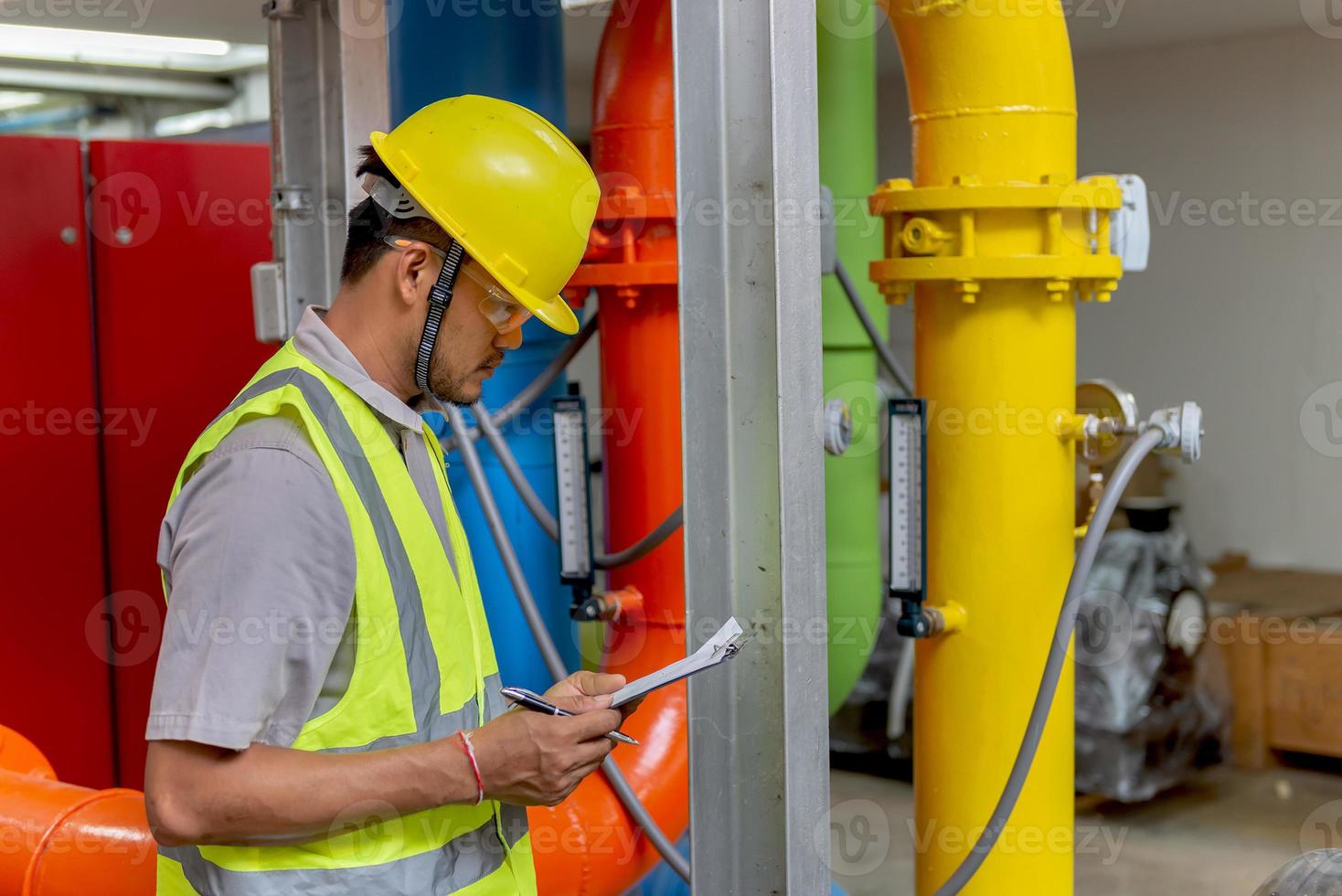 Asian engineer wearing glasses working in the boiler room,maintenance checking technical data of heating system equipment,Thailand people photo