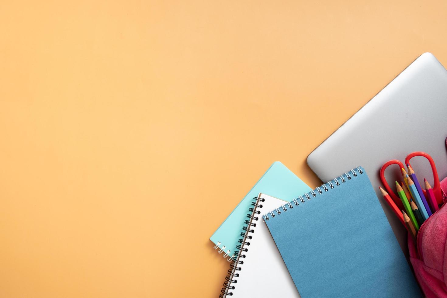 Stationary and laptop on colored background. Copy space. Kids work space top view, flat lay. Online learning concept photo