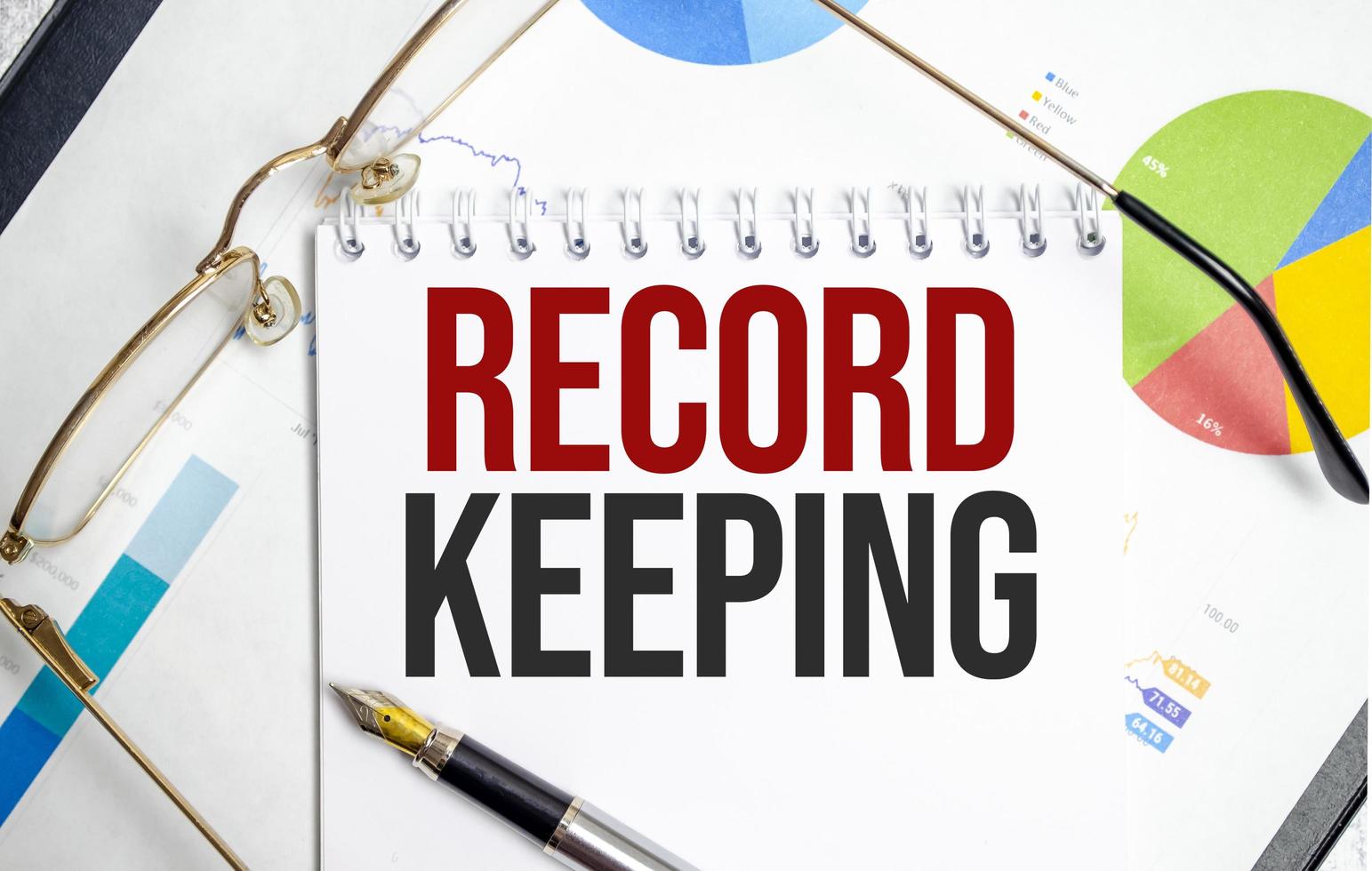RECORD KEEPING word on notepad with glasses and chart photo