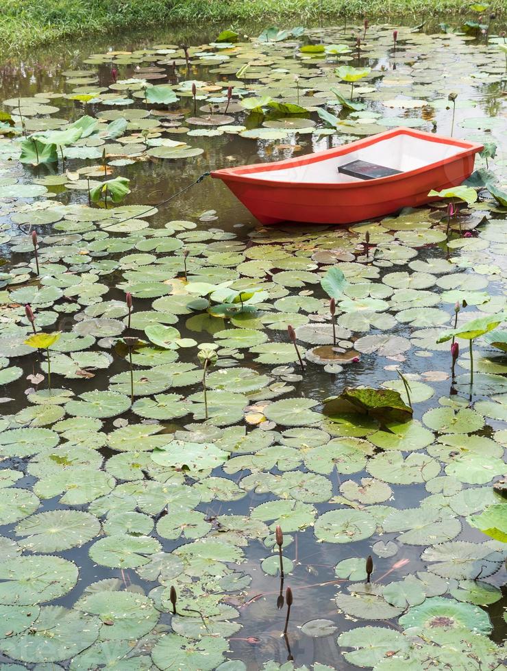 Red plastic boat in the small pond. photo