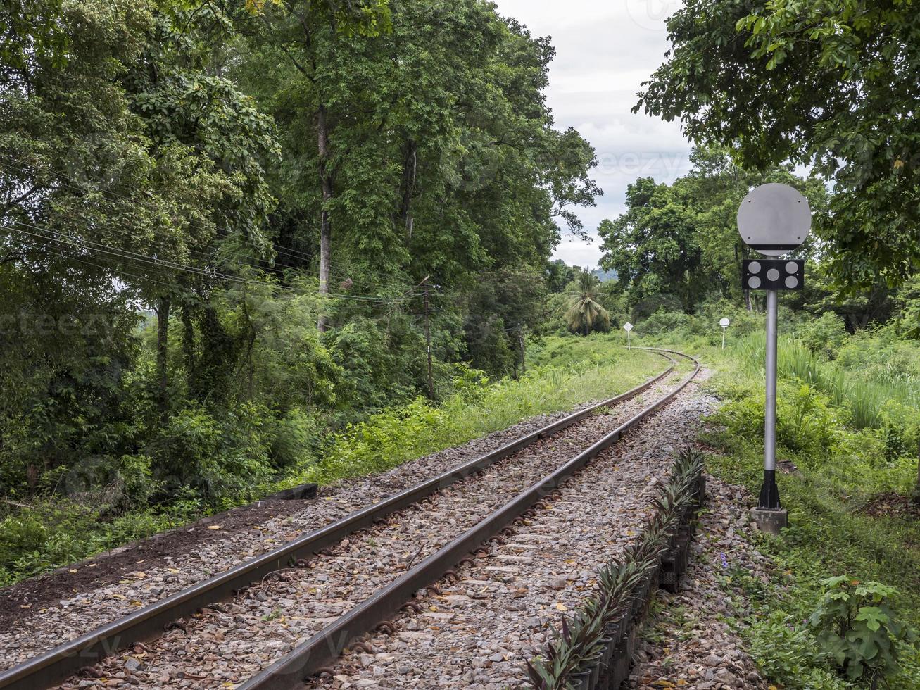 línea ferroviaria curva con el poste de la señal de tráfico. foto