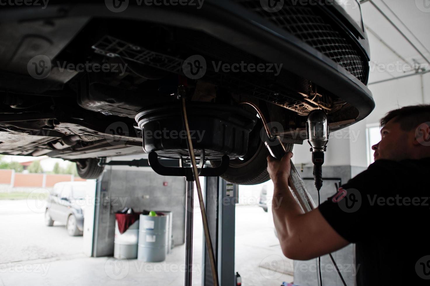 Car repair and maintenance theme. Mechanic in uniform working in auto service. photo
