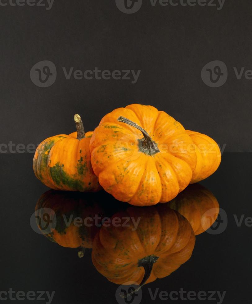 Pumpkins on a black background with reflection. photo