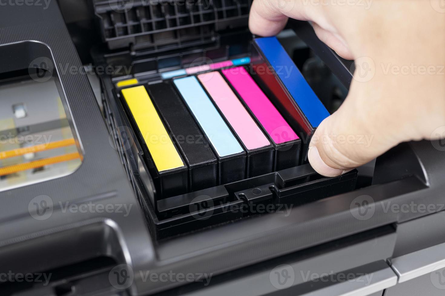 Human hand changing a blue ink cartridge of a multicolor inkjet printer photo