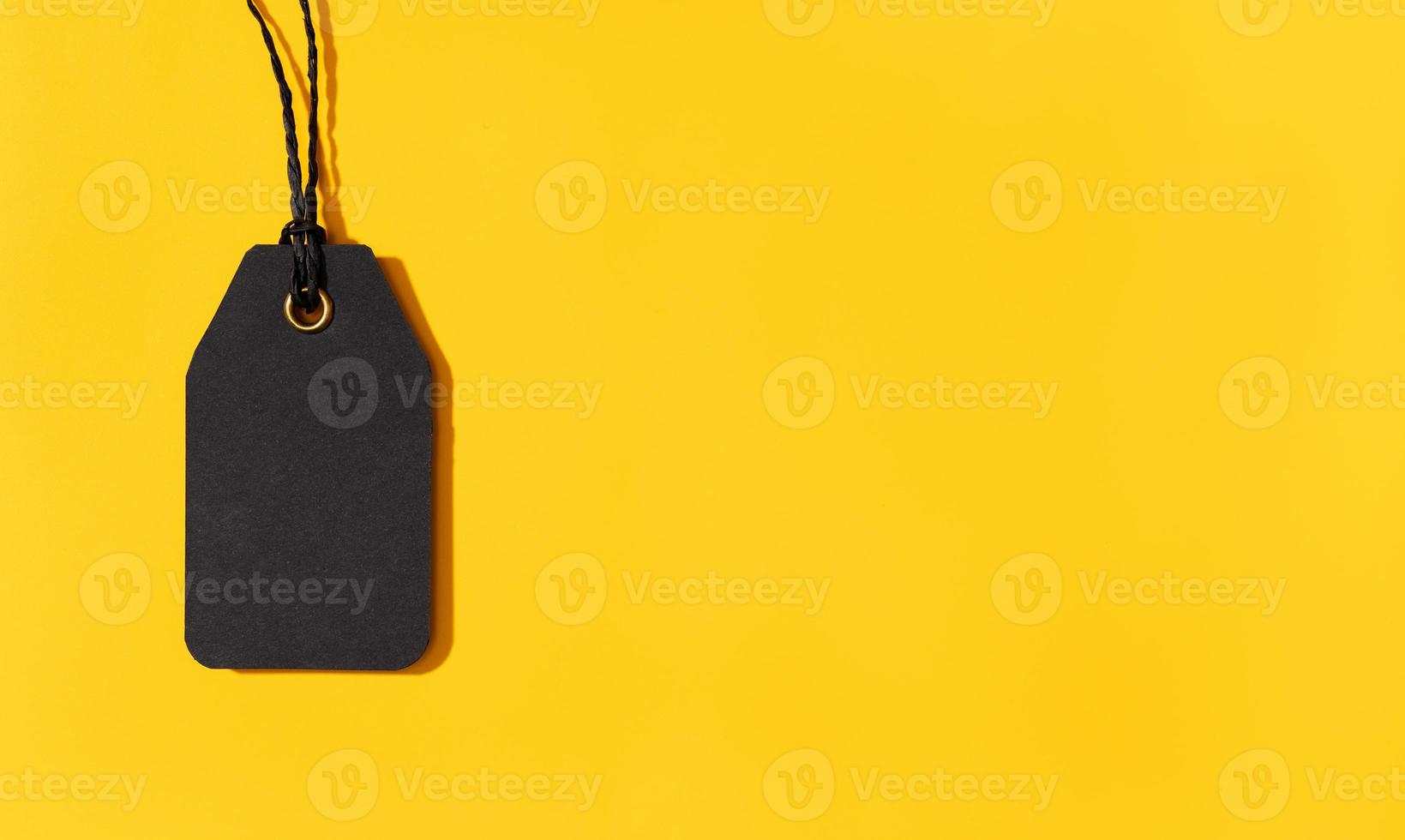 Blank black tag isolated on yellow background with copy space. Template Mock up photo