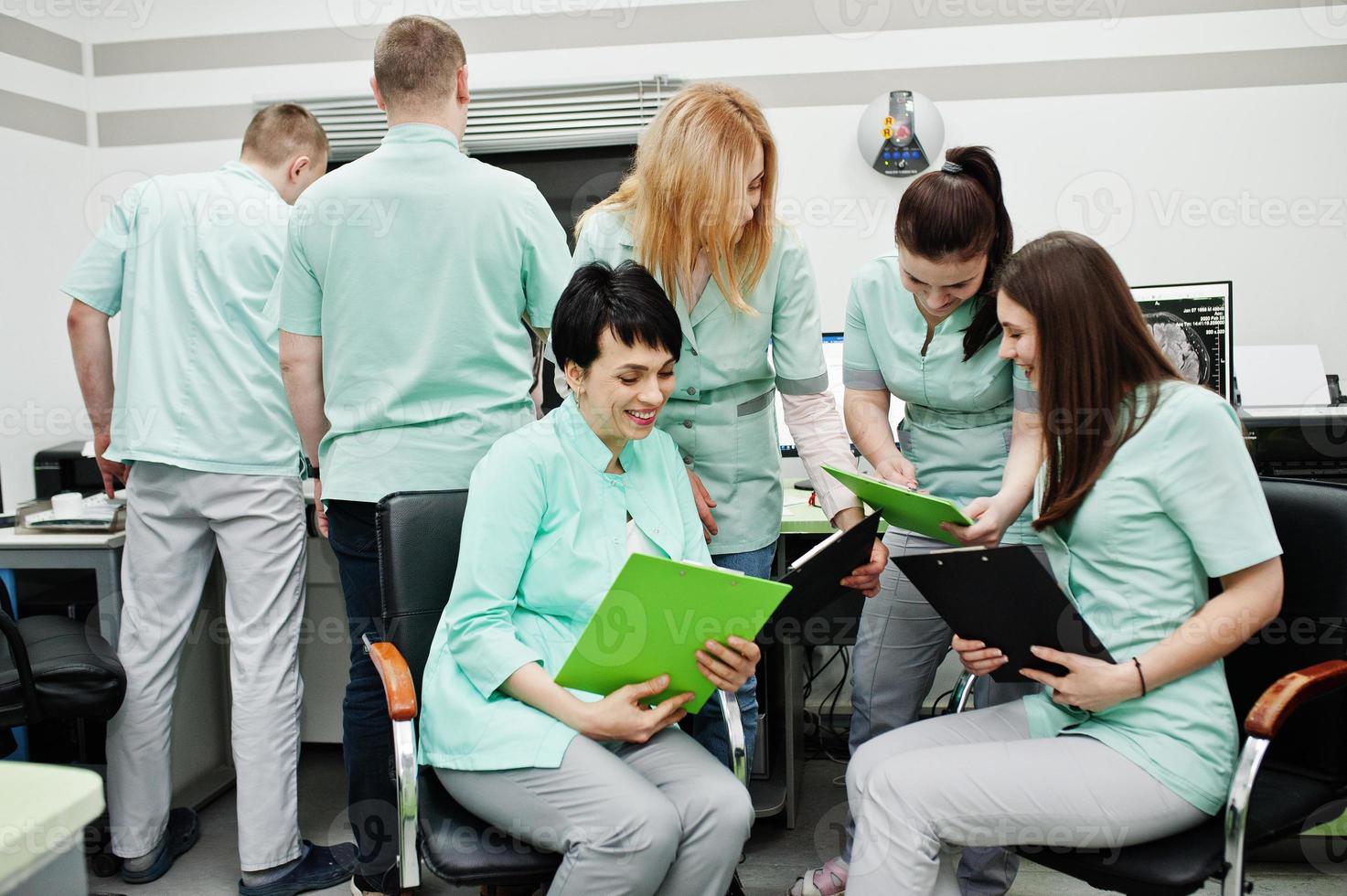 Medical theme.Observation room with a computer tomograph. The group of female doctors with clipboards meeting in the mri office at diagnostic center in hospital. photo