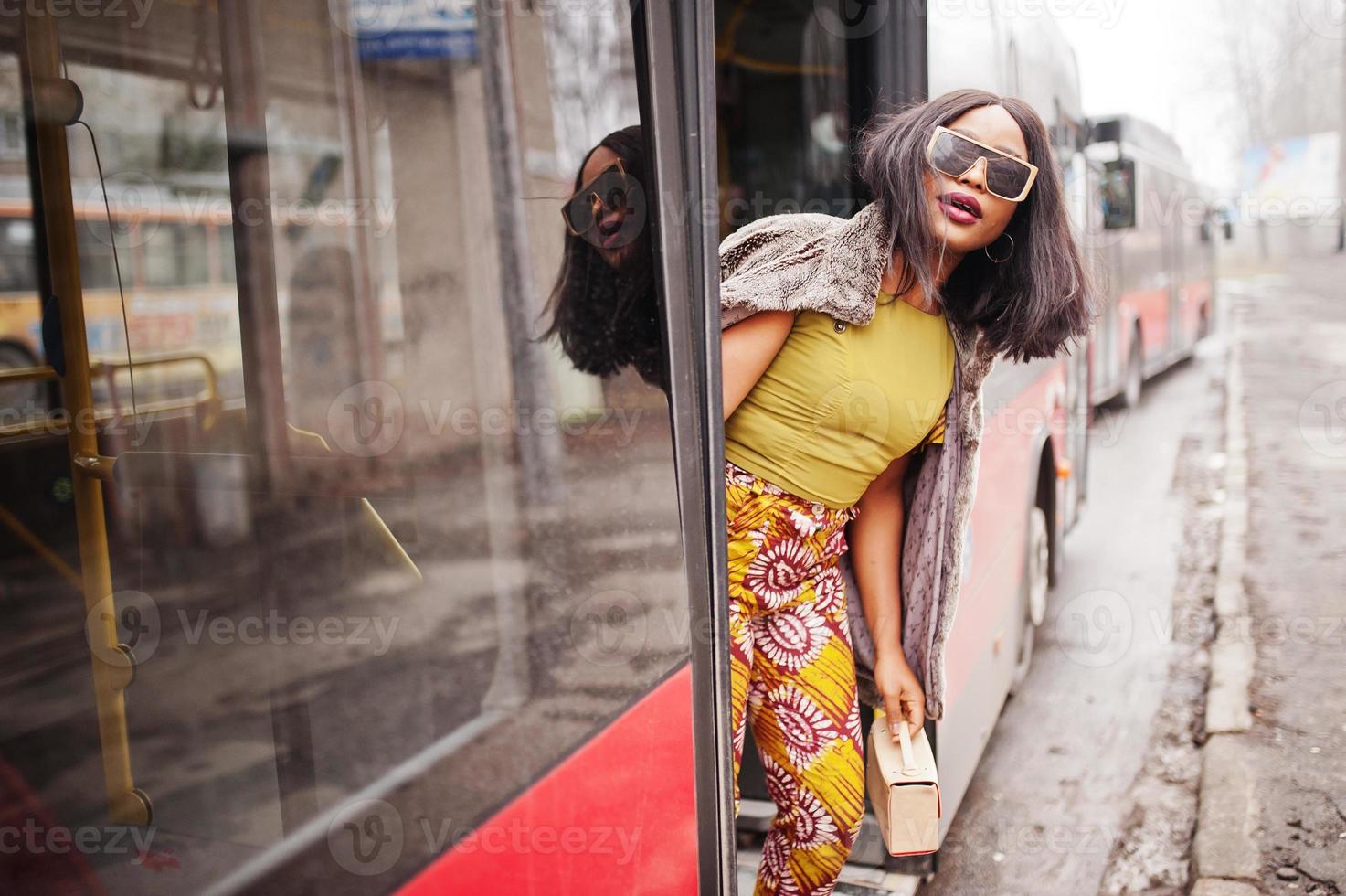 joven mujer afroamericana con estilo en gafas de sol modernas en un autobús. foto