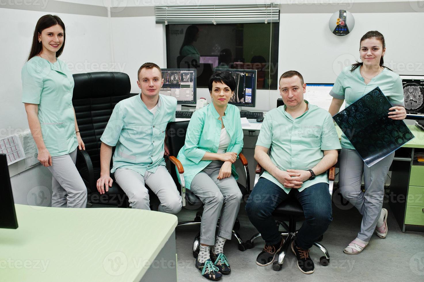 Medical theme.Observation room with a computer tomograph. The group of doctors meeting in the mri office at diagnostic center in hospital. Hold x-ray radiographic image. photo