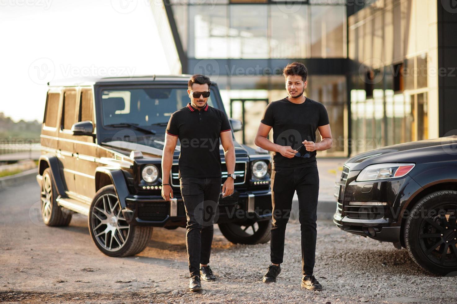 Two asian brothers man wear on all black posed near suv cars. photo