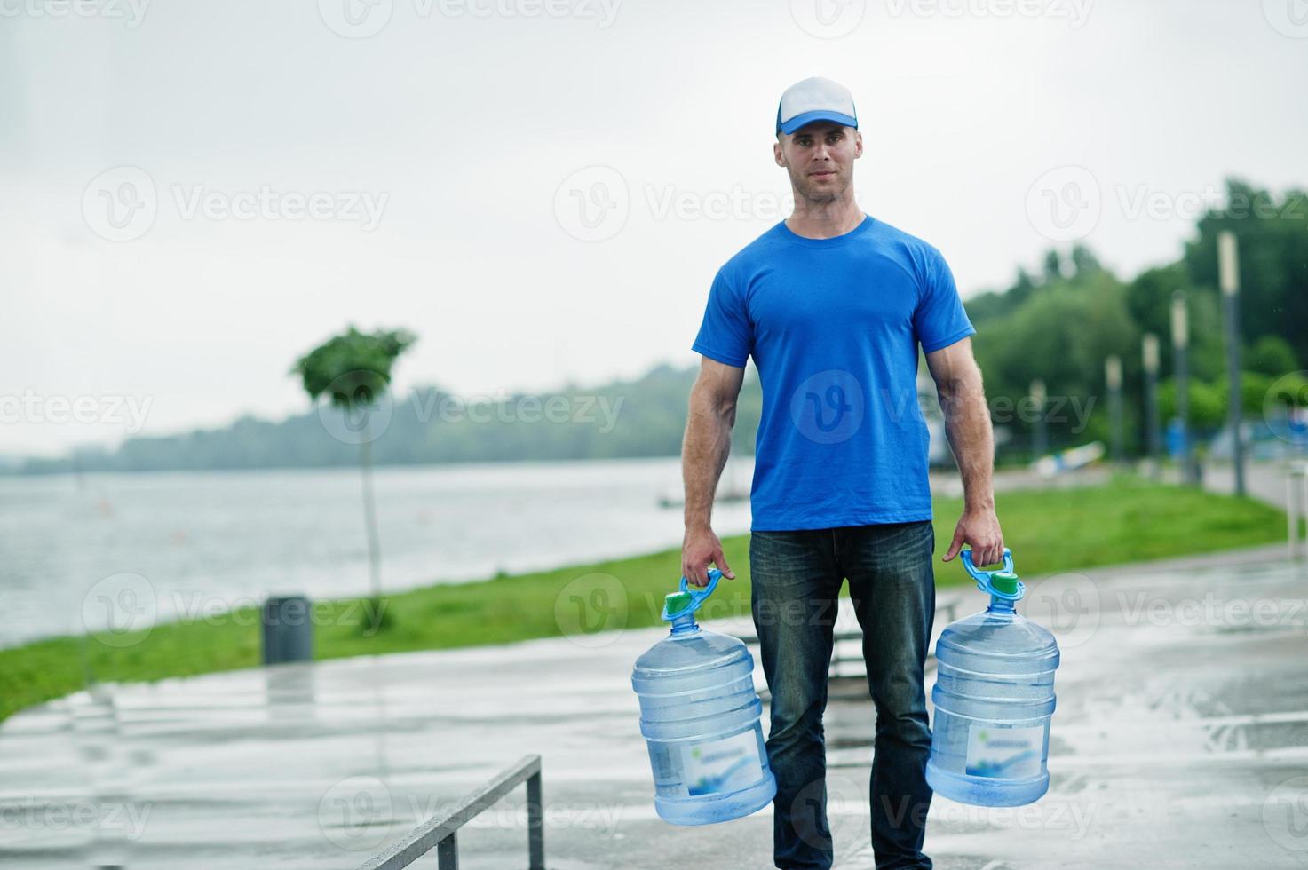 Delivery man with water bottles at hands. photo