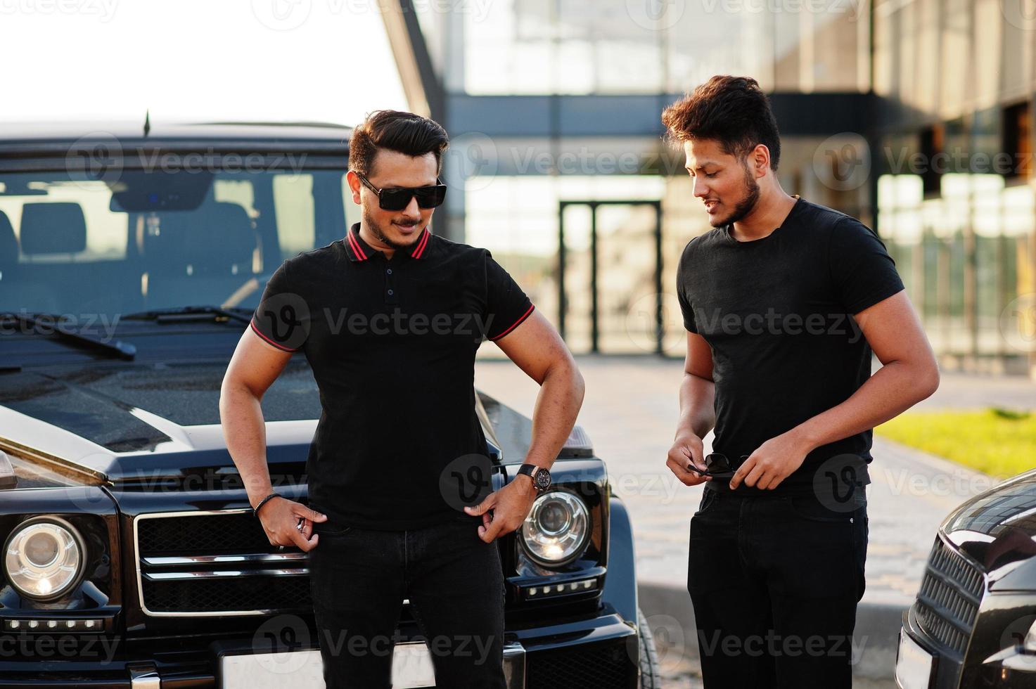 Two asian brothers man wear on all black posed near suv cars. photo