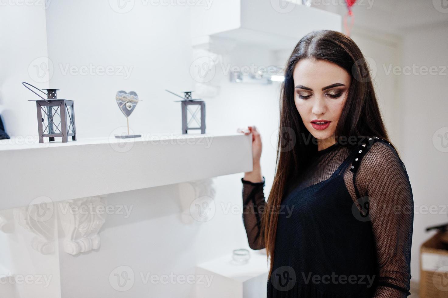 hermosa chica morena en la boutique de la tienda de ropa en vestido negro. foto