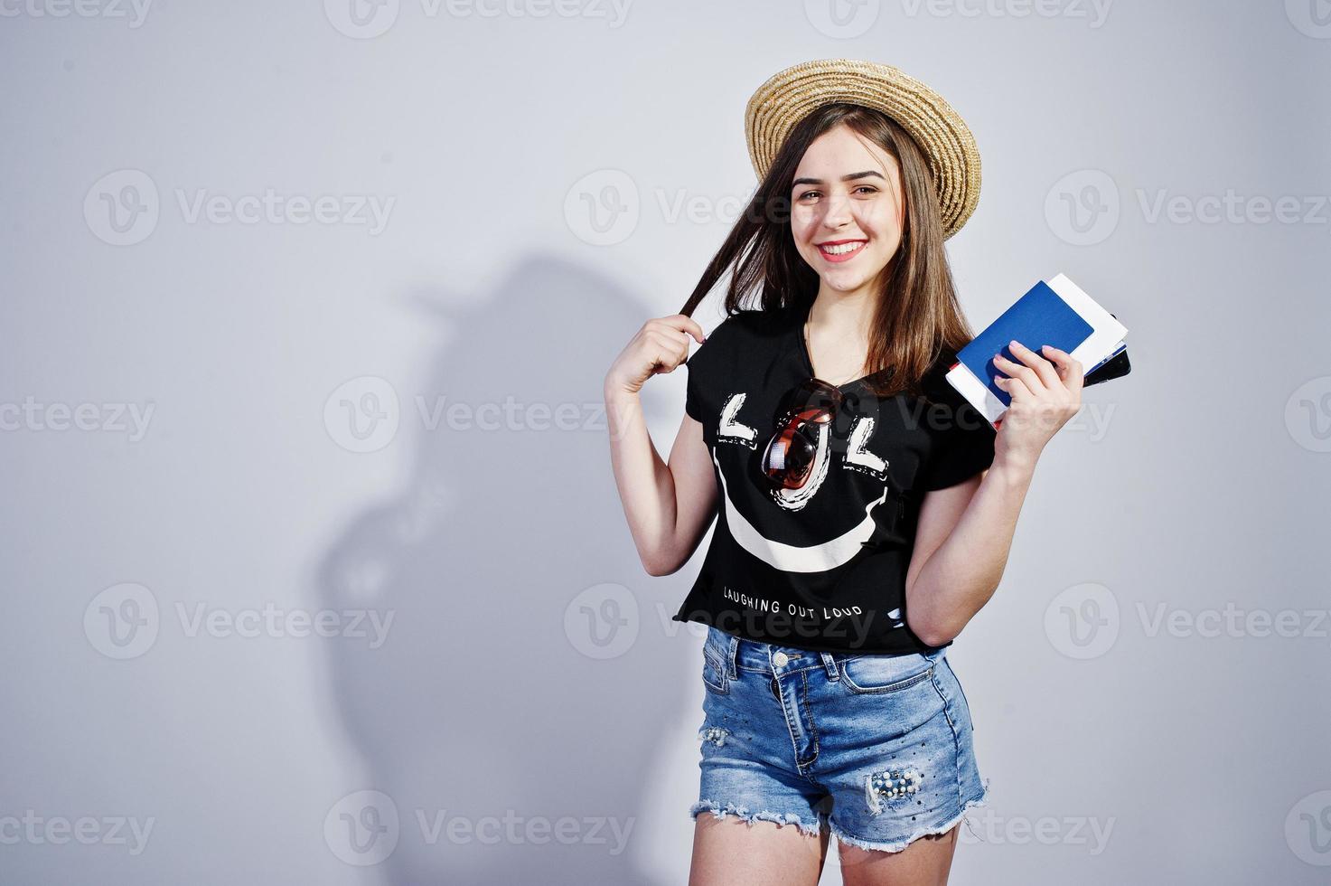 Girl tourist with passport, wear in lol shirt, shorts and hat isolated on white. photo