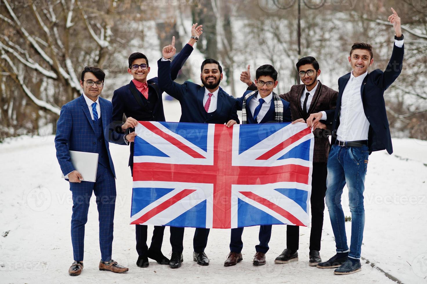 grupo de seis hombres de negocios indios en trajes posados al aire libre en un día de invierno en europa con bandera de gran bretaña. relaciones amistosas con la india y el reino unido. foto