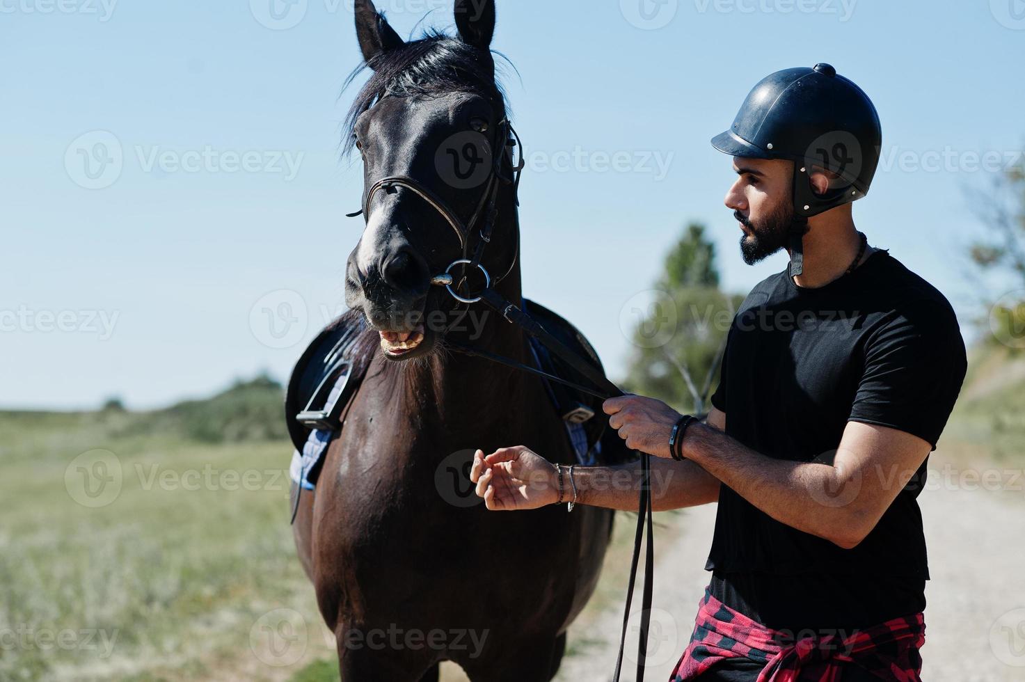 Arab tall beard man wear in black helmet with arabian horse. photo