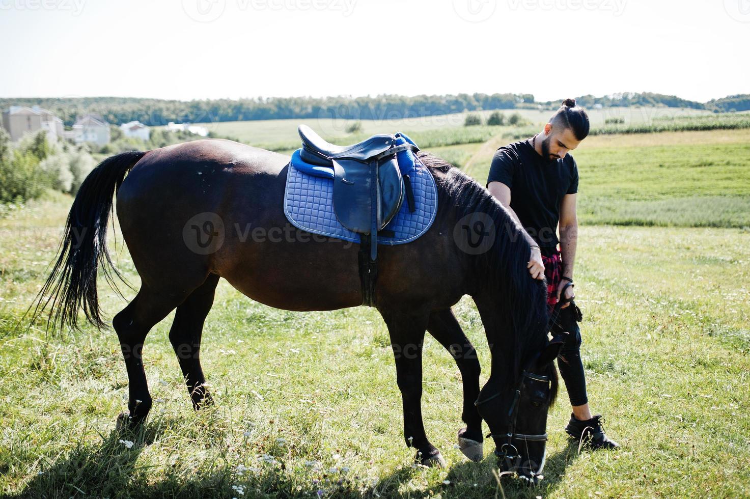 Arab tall beard man wear in black with arabian horse. photo