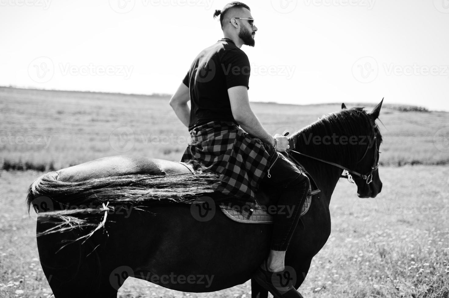 Arab tall beard man wear in black and sunglasses ride arabian horse. photo